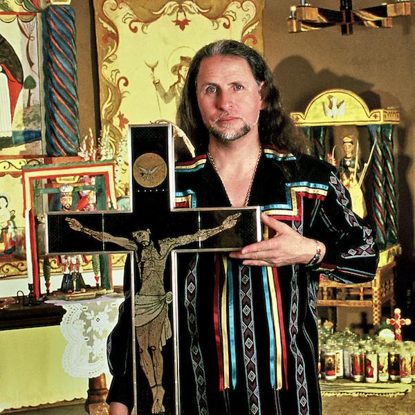 A man holding a carved crusifix.