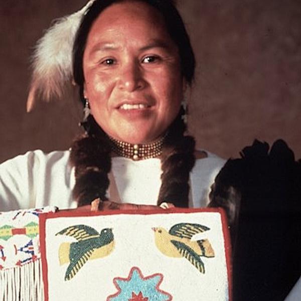 A woman holds up art work for the camera.