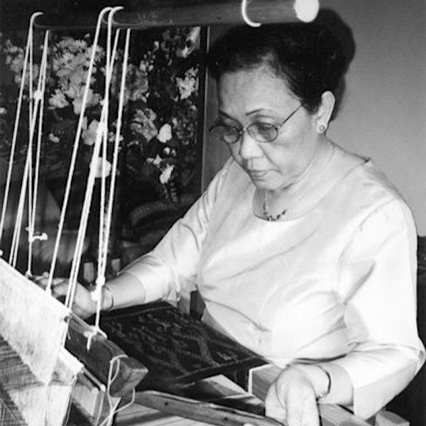 A woman sitting at a weaving loom.