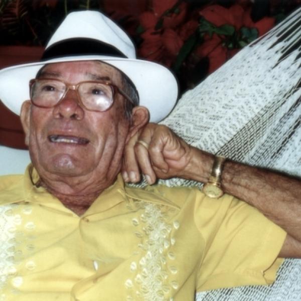 A man wearing a straw hat sitting in a hammoc.