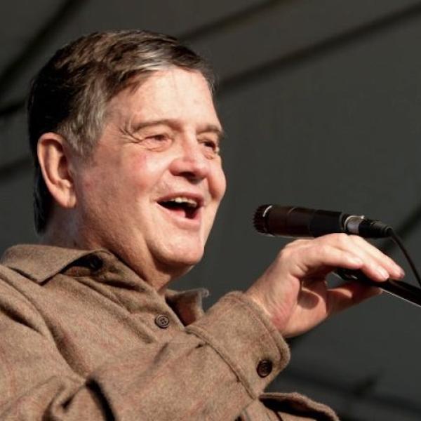 A man on satge speaking through a microphone.