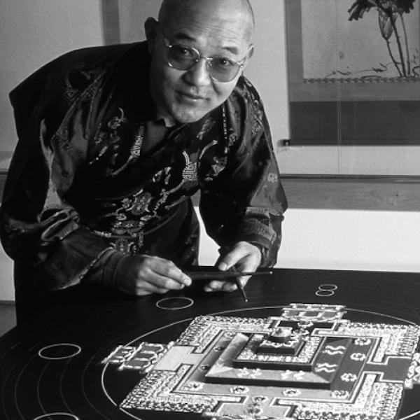 A man crouching over a table top artwork.