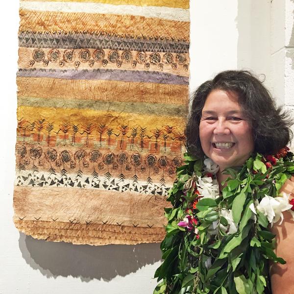 A woman poses next to a wall hanging.