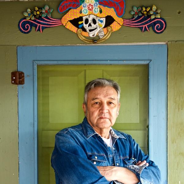 A man poses infront of a doorway crowned with a painted sculpture.