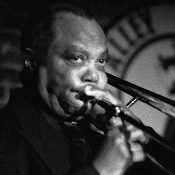 Man on stage playing trombone. 