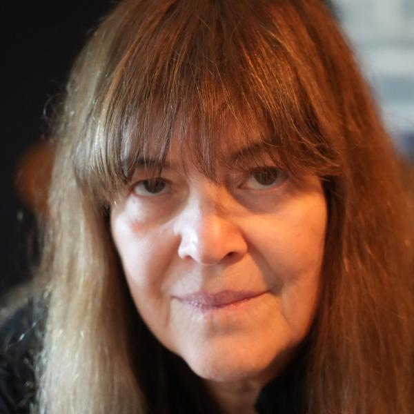 Close-up of white woman with long, straight brown hair staring into camera.