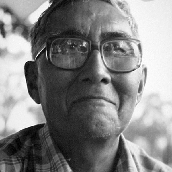 Portrait of older man with short hair wearing glasses, smiling. 