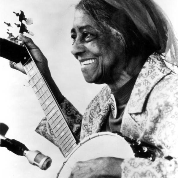 Older Black woman playing a guitar left-handed. 