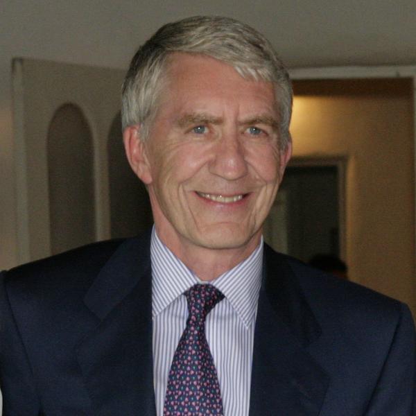 Portrait of white man with graying hair in a suit and tie. 