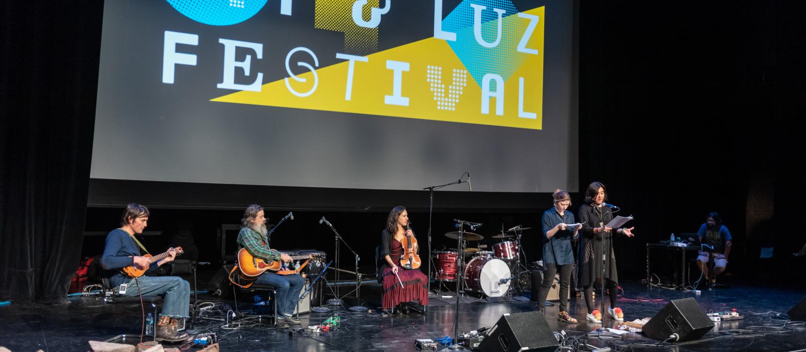 A band on stage with two readers in front of them.