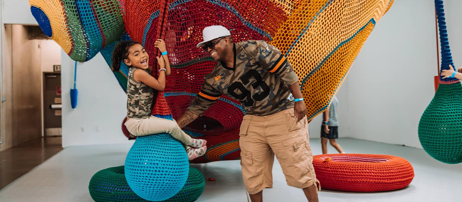 African American man and young daughter with colorful netting behind them