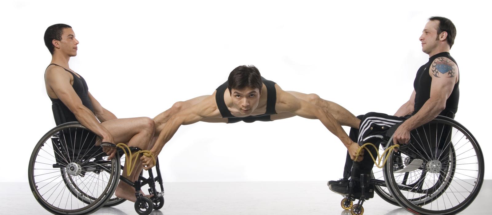 Three dances, one spread out with legs on dancers on each side of him sitting in wheelchairs