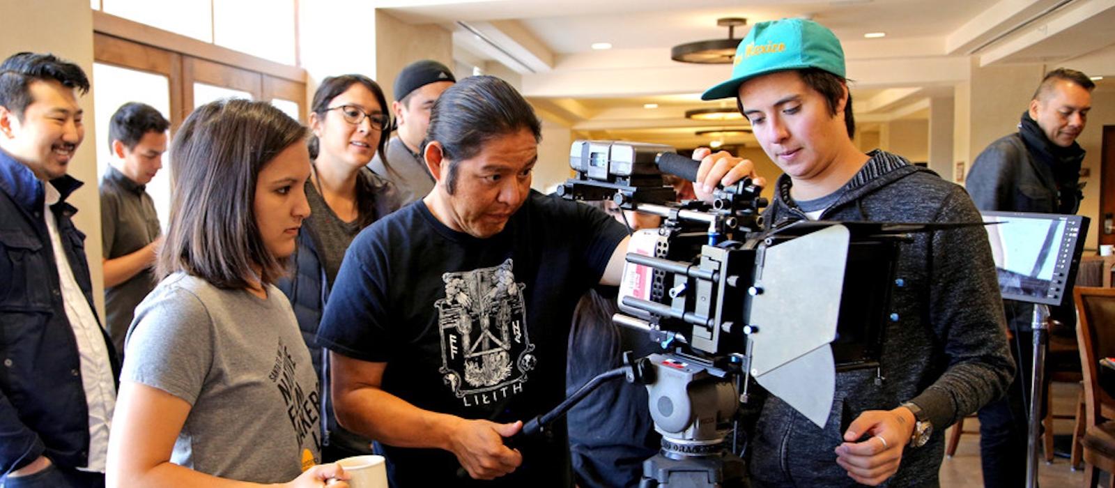Closeup of two men and one women filmmakers setting up an indoor camera shot