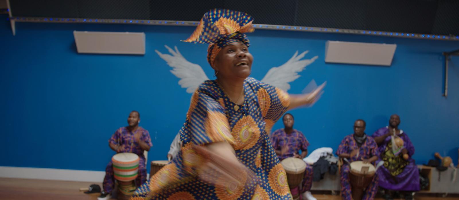Woman in African garb dancing in dance studio.