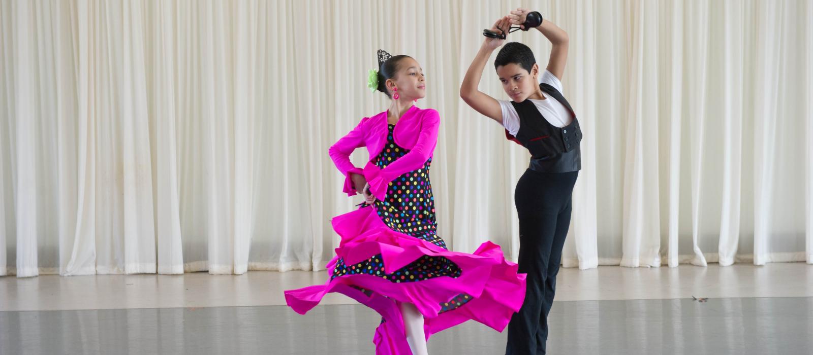Two children, dressed in flamenco clothing, in a dance pose.