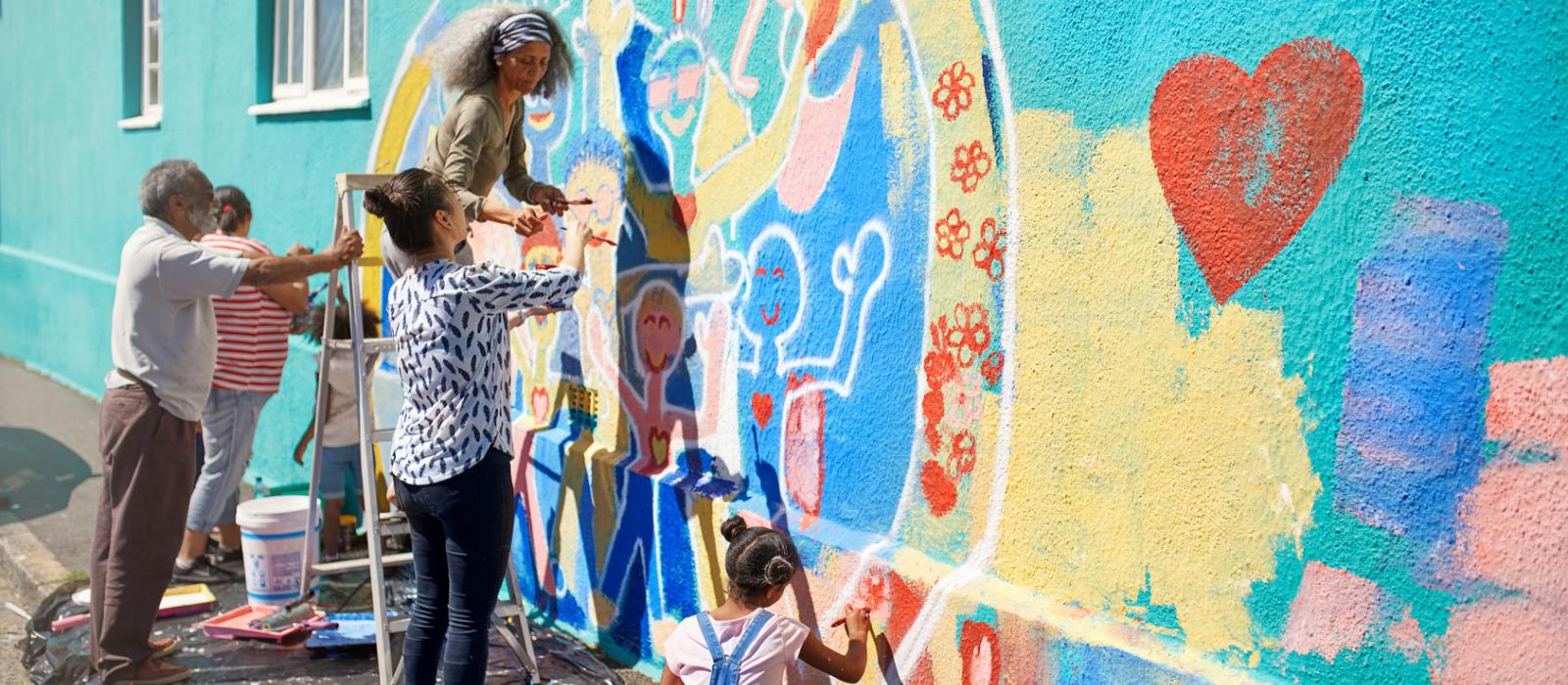 Group of you people and adults working on a mural 