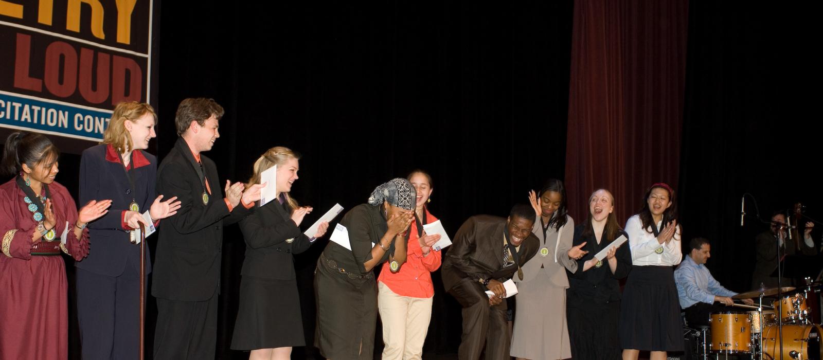 Teenager crying on stage with other teenagers after winning contest.