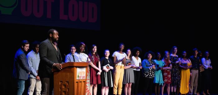 Students stand in a line on stage.
