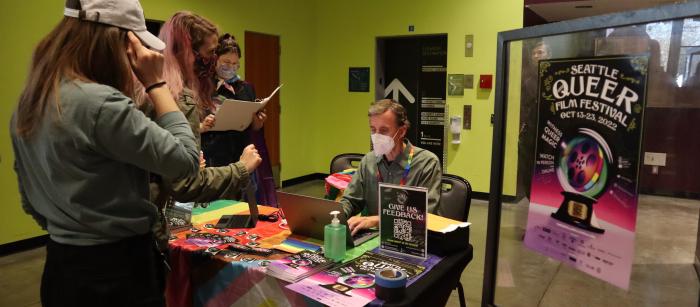 a group of people buying tickets from someone behind a table