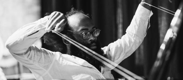 Black man with glasses conducting an orchestra.