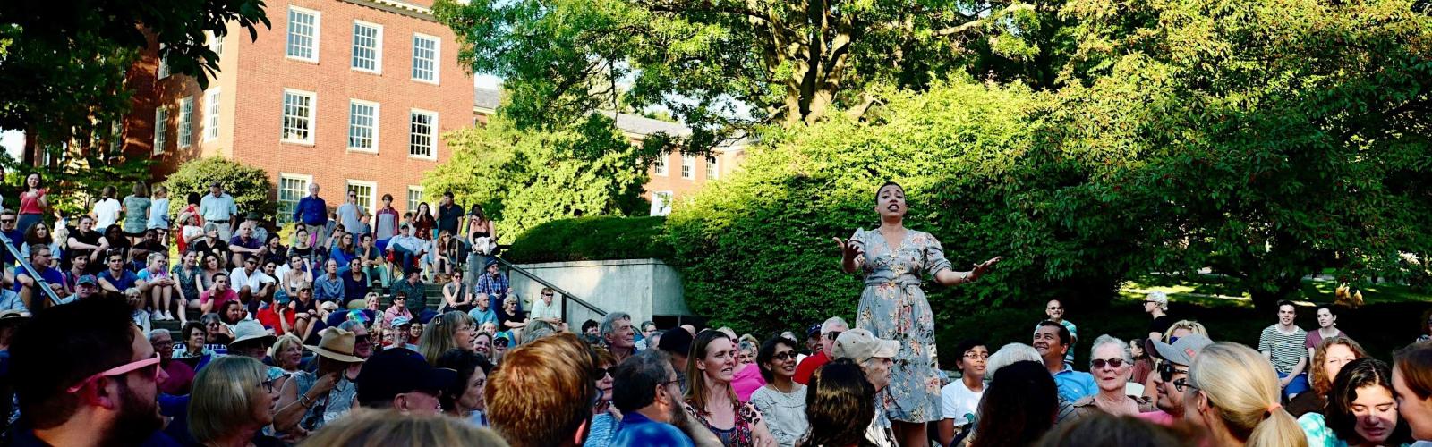 Woman singing in front of large crowd.