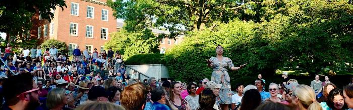 Woman singing in front of large crowd.