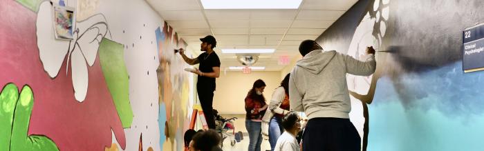 Group of people painting mural on inside walls of building. 