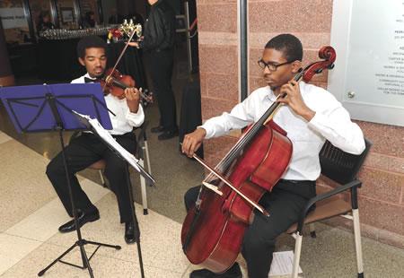 Two young men performing, one playing the violin, the other the cello