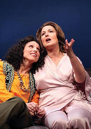 Two actresses - one expostulating the other next to her with head on shoulder