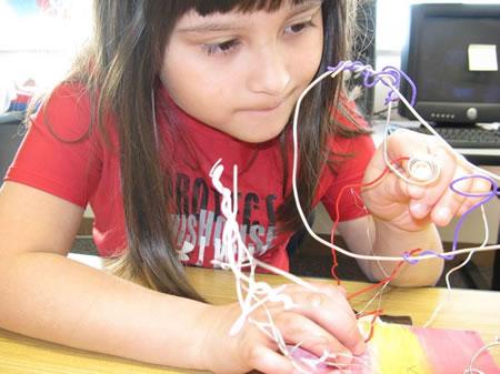 A second-grader at Quatama Elementary in Hillsboro, Oregon, lights the sculpture she created when a visual arts residency was integrated with the study of electrical circuits. Photo by Janis Hill
