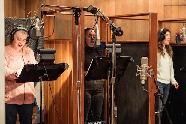 Three people in recording booths.