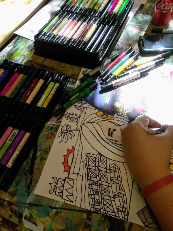 A pair of hands use a variety of markers to create a picture