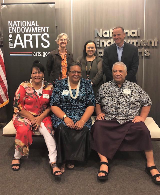 Two rows of people standing in front of the NEA sign