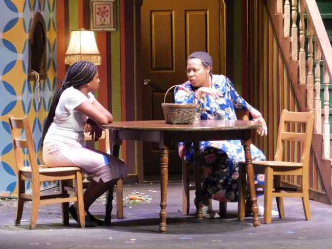 Two actresses sit at a table onstage in a production of August Osage County