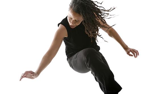 An African-American woman searing a sleeveless black shirt dancing with her eyes closed. 