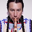 Headshot of a man playing a flute.
