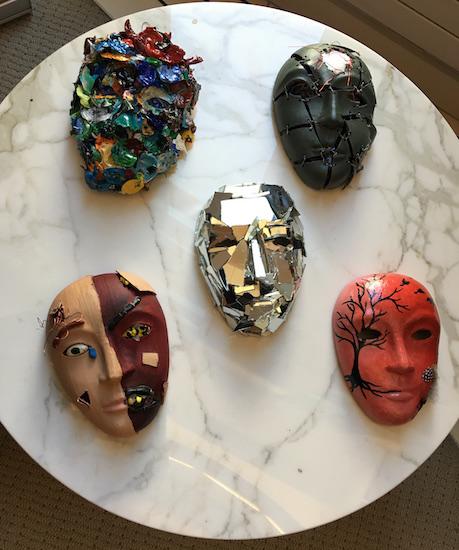  a tabletop laid with 5 different types of masks made in creative arts therapy sessions