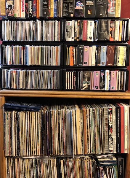 shelves stuffed with compact discs, records, and music-related VHS tapes