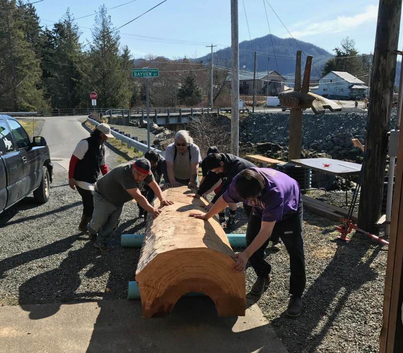 Men move a large cut log Men transfer a large cut log