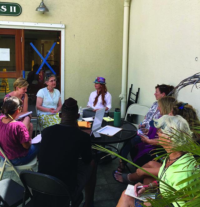 Federal and local officials meet in the Virgin Islands People sit around an outdoor table in a tropical environment