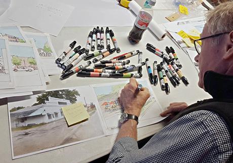 Man at a design desk working on draft drawings with lots of sharpies and drawi