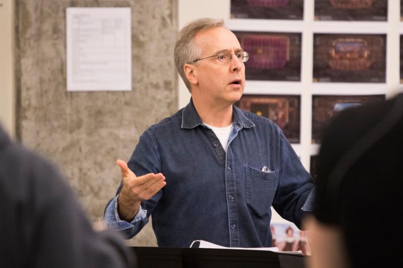 Man with glasses conducting an orchestra.