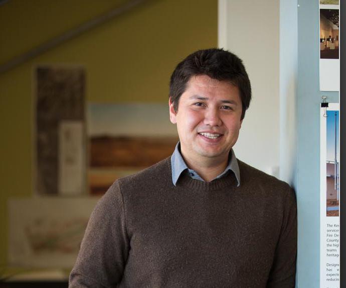 Man smiling and leaning against a wall