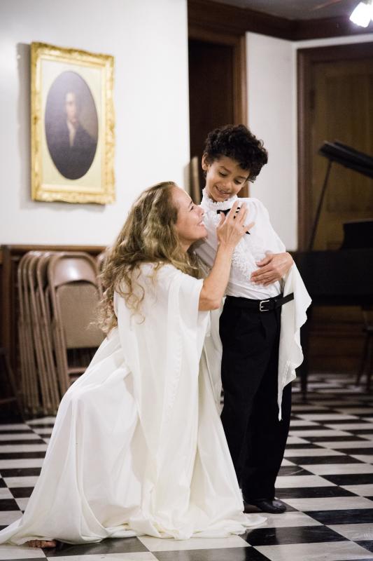 A scene from La Pasion de Poe A smiling woman in white kneels next to a young boy in a tuxedo