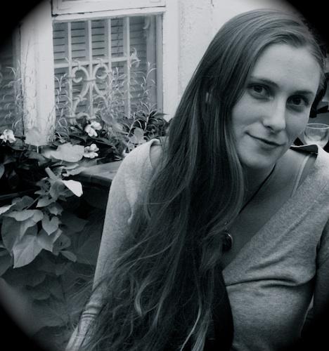 a young white woman with long dark hair sits in a back garden