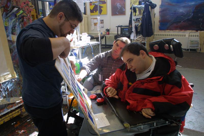 Man pointing to colors for man in wheelchair to choose.