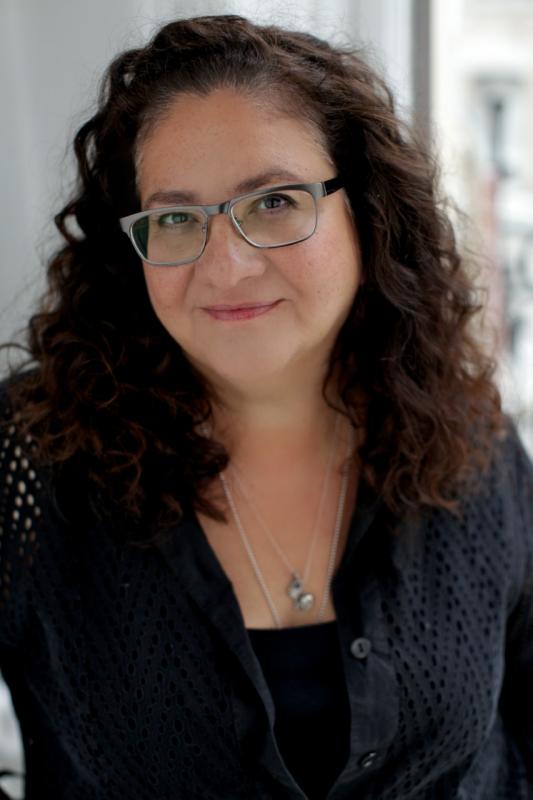 MIgdalia Cruz Woman with long wavy hair and glasses