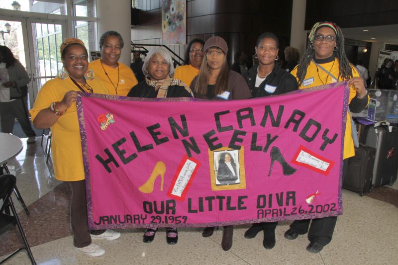 Women holding up an AIDS Quilt panel. 