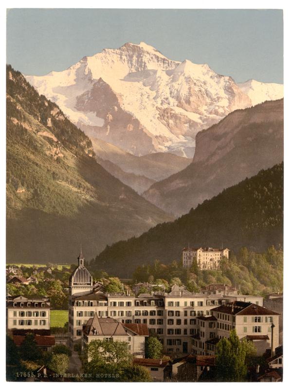 Buildings at the foot of a majestic snow-covered mountain. 