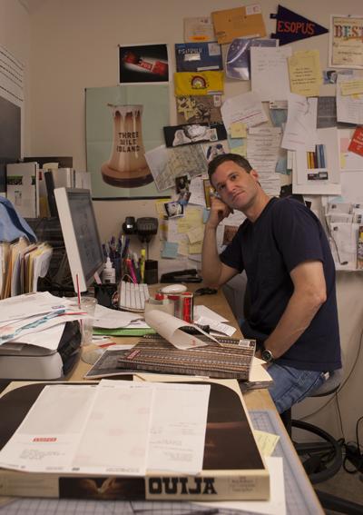 Man sitting at desk in messy office. 